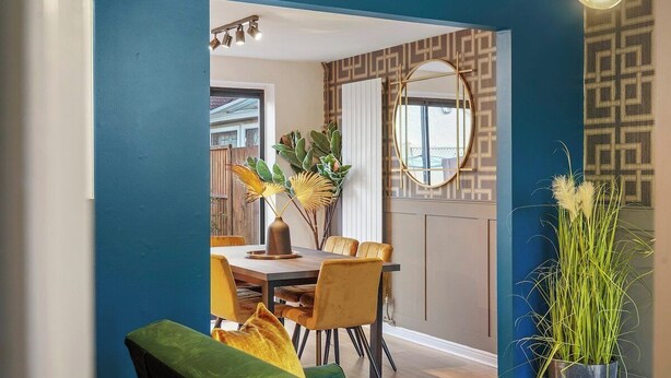 Un espace repas comprenant une table et des chaises, un miroir et des plantes décoratives.