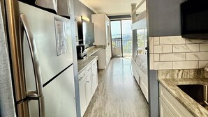 A modern kitchen with stainless steel appliances, a marble backsplash, and a view to the outside. - Perrydise@ Pirates' Bay Top-Floor Studio with Panoramic Sound Views, Pools, Dock (Fort Walton Beach)