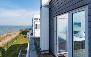 A modern seaside property with a balcony overlooking the ocean, a large sliding glass door, and a view of the sea. - Nice home in Olpenitz with sauna (Olpenitz)