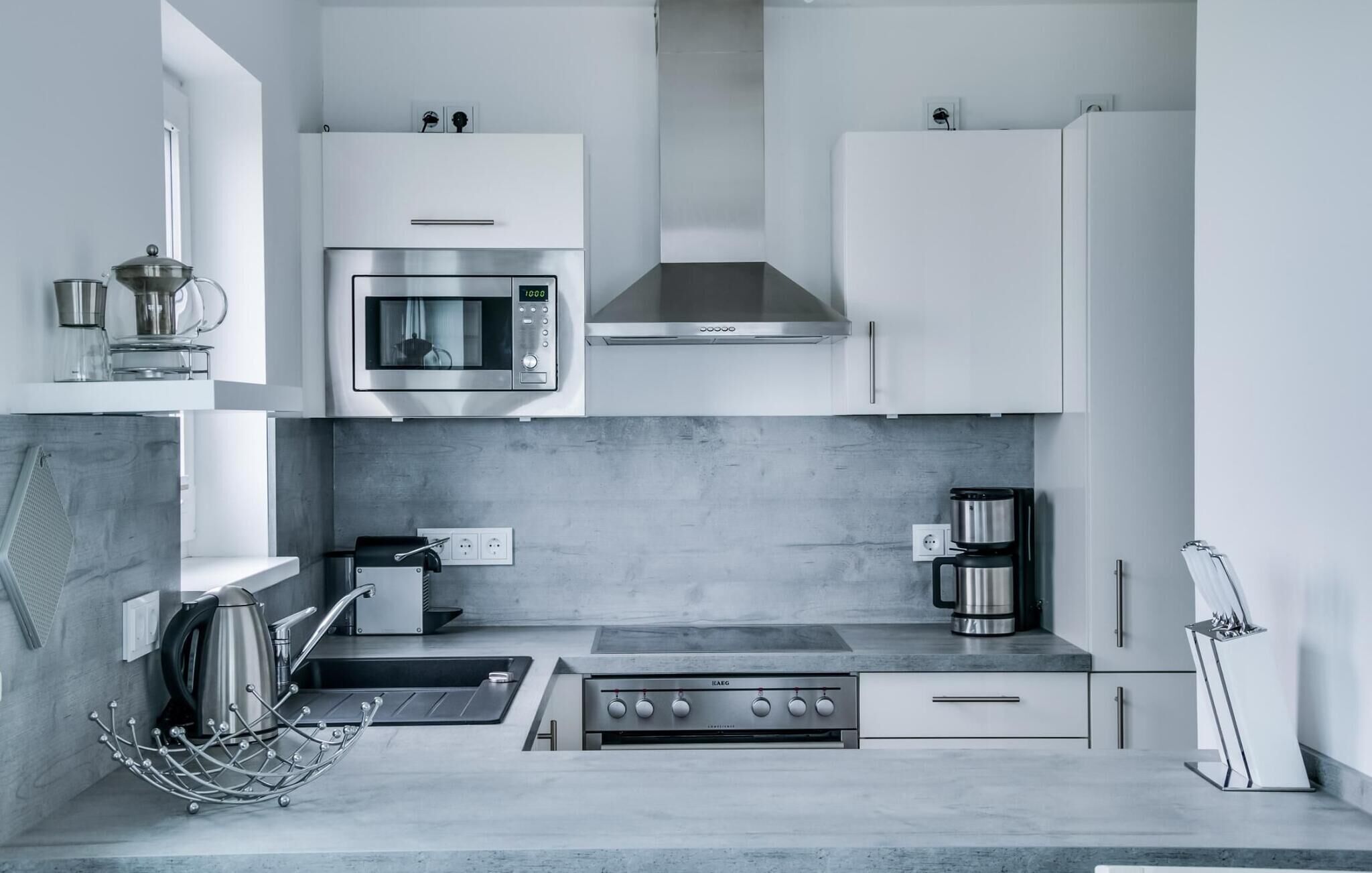 A modern kitchen with a built-in microwave, stove, and coffee maker.