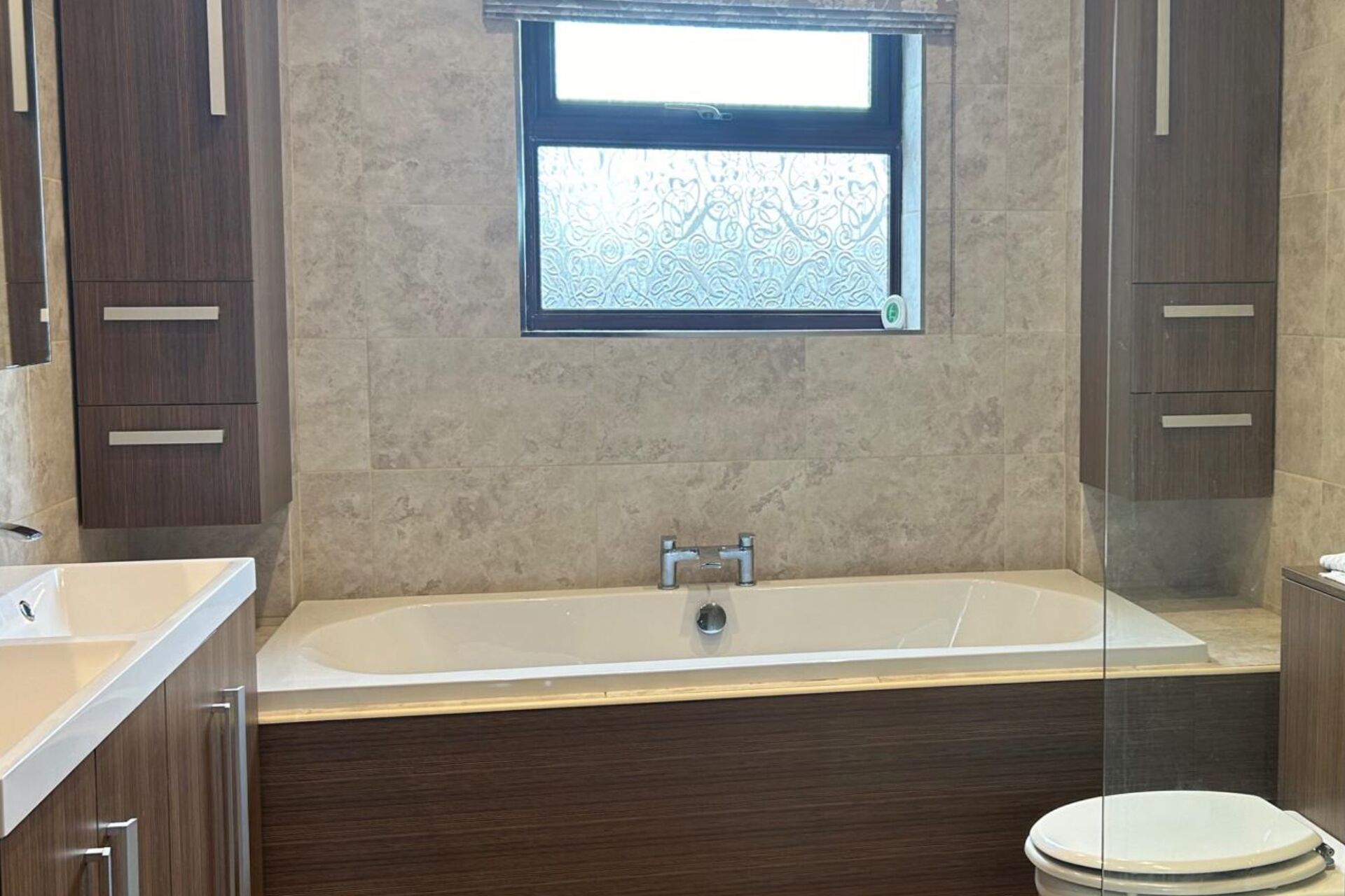 Une salle de bain moderne avec une baignoire sur pieds, une fenêtre au-dessus du lavabo et des meubles en bois.