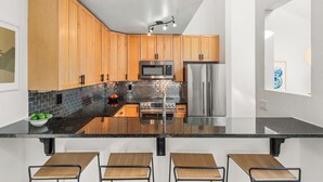 A modern kitchen with wooden cabinets, stainless steel appliances, and a black countertop. - Chic Mountain Getaway on Shuttle Route (Snowmass Village)