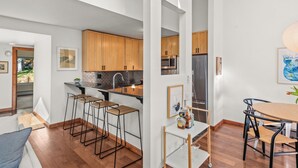 A modern kitchen with wooden cabinets, a stainless steel refrigerator, and a bar area with stools. - Chic Mountain Getaway on Shuttle Route (Snowmass Village)