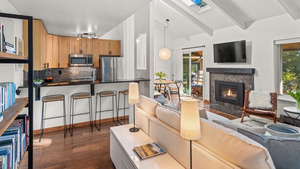 A modern living room with a fireplace, a kitchen with wooden cabinets, and a dining area. - Chic Mountain Getaway on Shuttle Route (Snowmass Village)