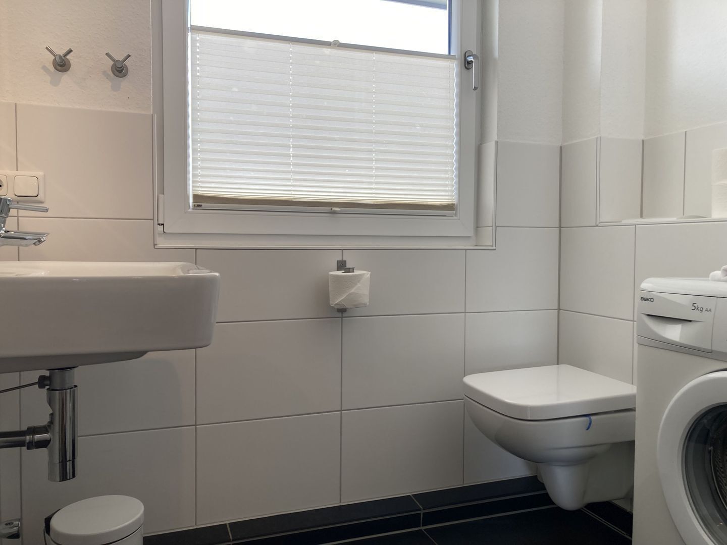 Ein Badezimmer mit Waschbecken, Toilette und Waschmaschine.