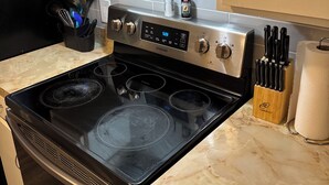 A kitchen with a black stove, white cabinets, and a marble countertop. - Cozy 1-bedroom apartment with AC, WiFi and Washer/Dryer in Irving (Irving)