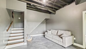 A modern living room with a grey couch, a wooden staircase, and exposed ductwork on the ceiling. - Breathtaking Views of Dale Hollow Lake (Monroe)