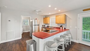 A modern kitchen with a central island, wooden cabinets, and a large window. - Breathtaking Views of Dale Hollow Lake (Monroe)