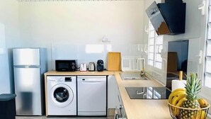 Eine kleine Küche mit Waschmaschine, Mikrowelle und Spüle.