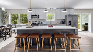 Una cocina moderna con una isla grande, taburetes de bar y un comedor con sillas.