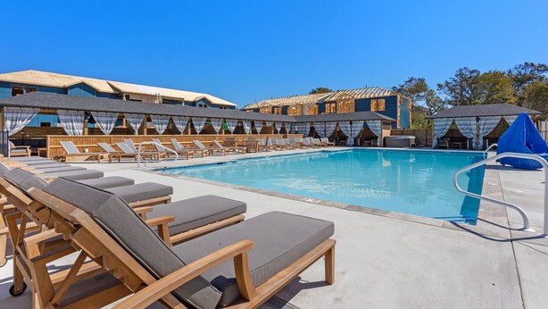 Un espace aménagé au bord de la piscine, avec des chaises longues et une piscine.