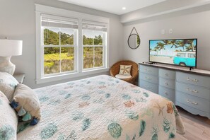 A bedroom with a large bed, a TV on a dresser, and a view of the outdoors through the window. - Coastal family escape w/ easy beach access & community pool (Kill Devil Hills)