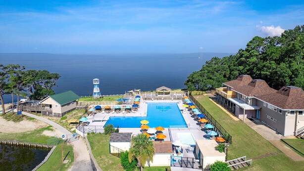 Una località turistica con una piscina grande, posti a sedere all'aperto e vista sull'oceano.