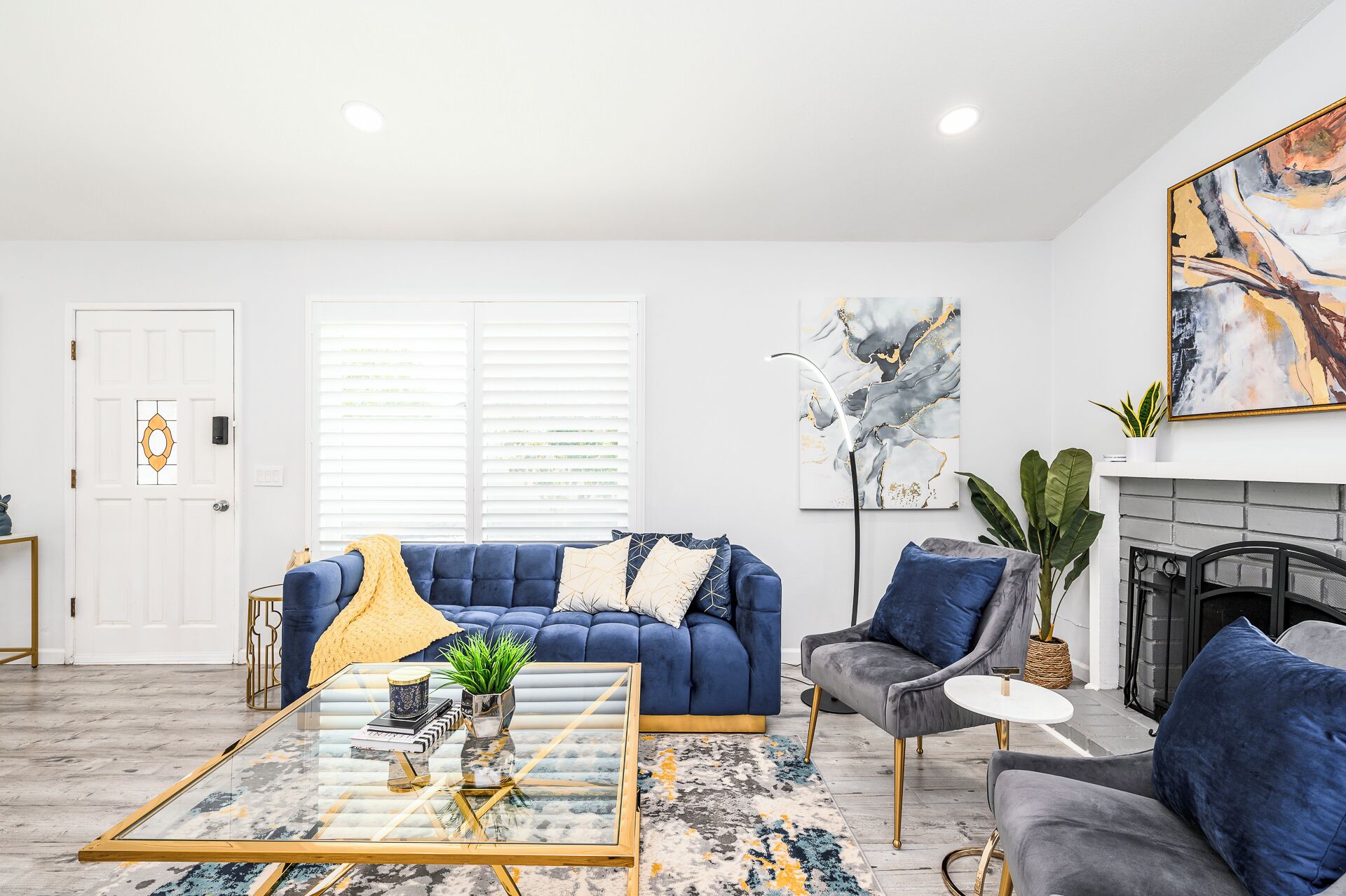 Ein modernes Wohnzimmer mit einem blauen Sofa, einem Glastisch und einem Kamin.