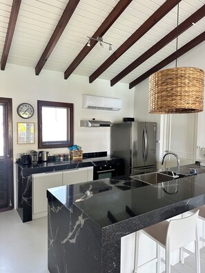 A modern kitchen with a marble island, stainless steel appliances, and a large window. - Villa Veva fully equipped Waterfront Escape (Kralendijk)