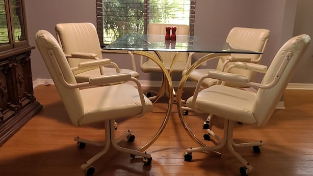 Une salle de conférence avec une table en verre et quatre chaises blanches à roulettes.