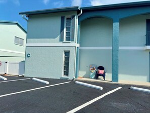 A parking lot with marked spaces and a building with a light blue exterior and a small porch area.