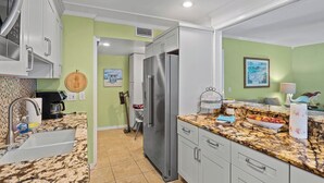 A kitchen with white cabinets, a granite countertop, and a stainless steel refrigerator. - 10125 Coral Coconut Cay - Condominium 2 Bedroom / 2 1/2Bath waterfront, maximum occupancy of 6 people. Community pool. (Bradenton)