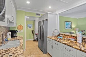 Una cucina con mobili bianchi, un piano di lavoro in granito e un frigorifero in acciaio inossidabile.