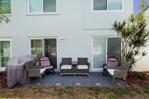 Un patio con mobili da esterno, una griglia coperta e una porta scorrevole in vetro.