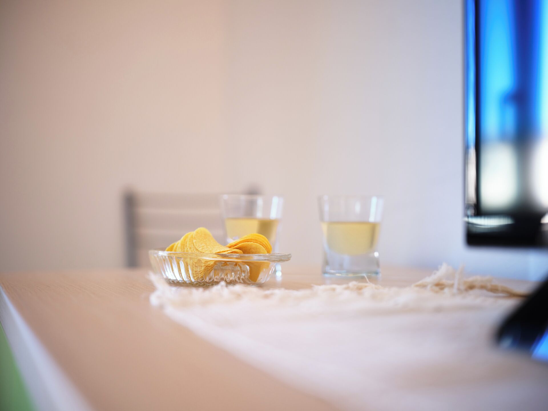 Une table avec un bol de collations et deux verres contenant une boisson claire.
