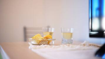 Une table avec un bol de collations et deux verres contenant une boisson claire.