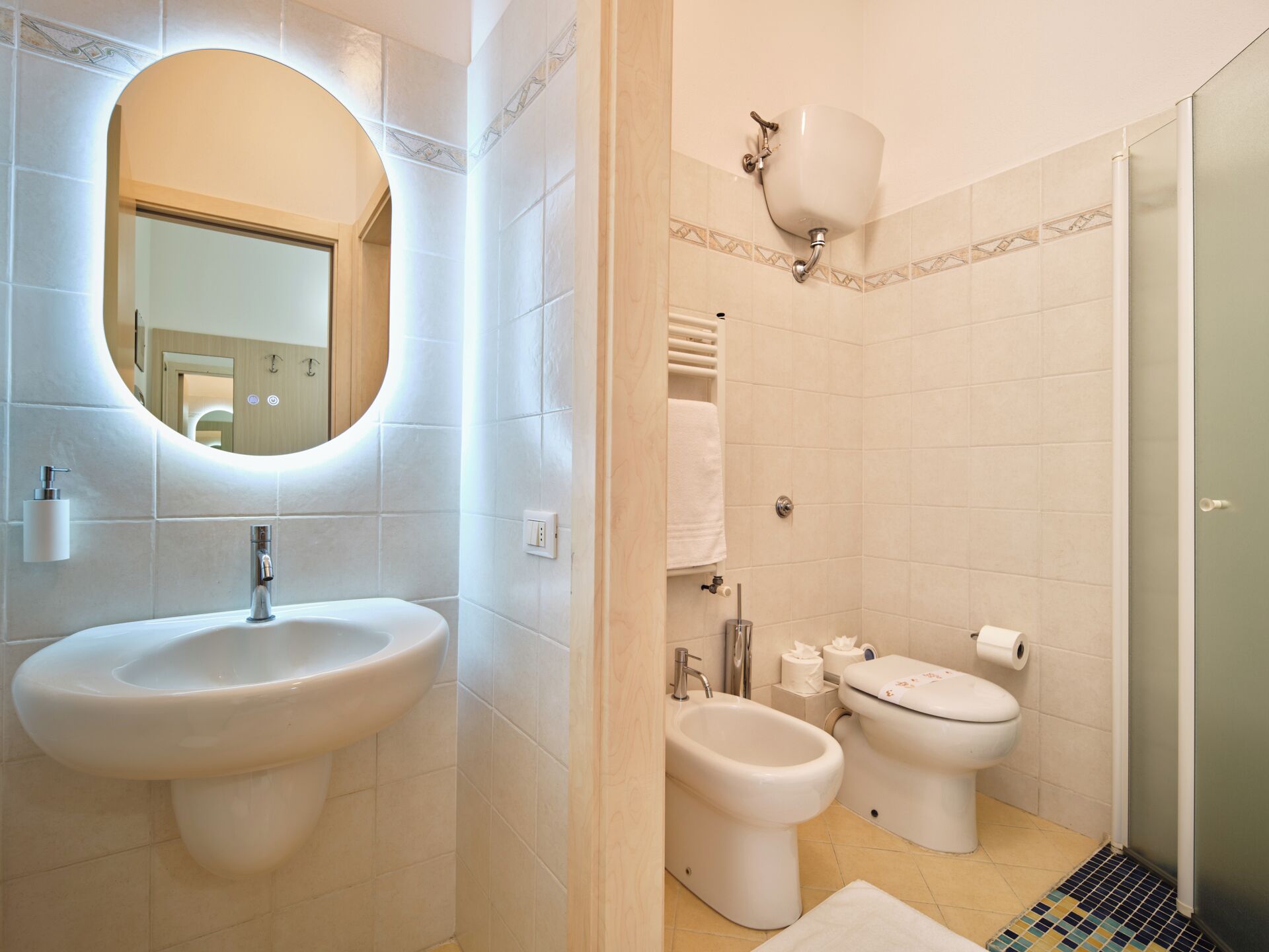 A bathroom with a sink, bidet, toilet, and a mirror.