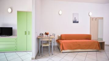 A compact room with a bed, a desk with a chair, a television, and a wardrobe.