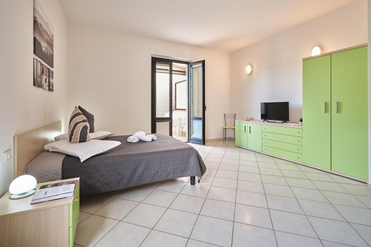 Ein modernes Schlafzimmer mit einem Bett, einem Fernseher und einem grünen Kleiderschrank.
