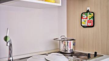 A kitchen with a stainless steel sink, a stove, and a pot on the counter.