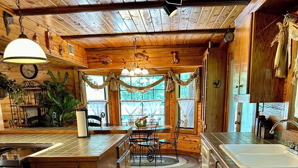 Interior d'una cabana de fusta amb cuina, zona de menjador i una finestra gran.