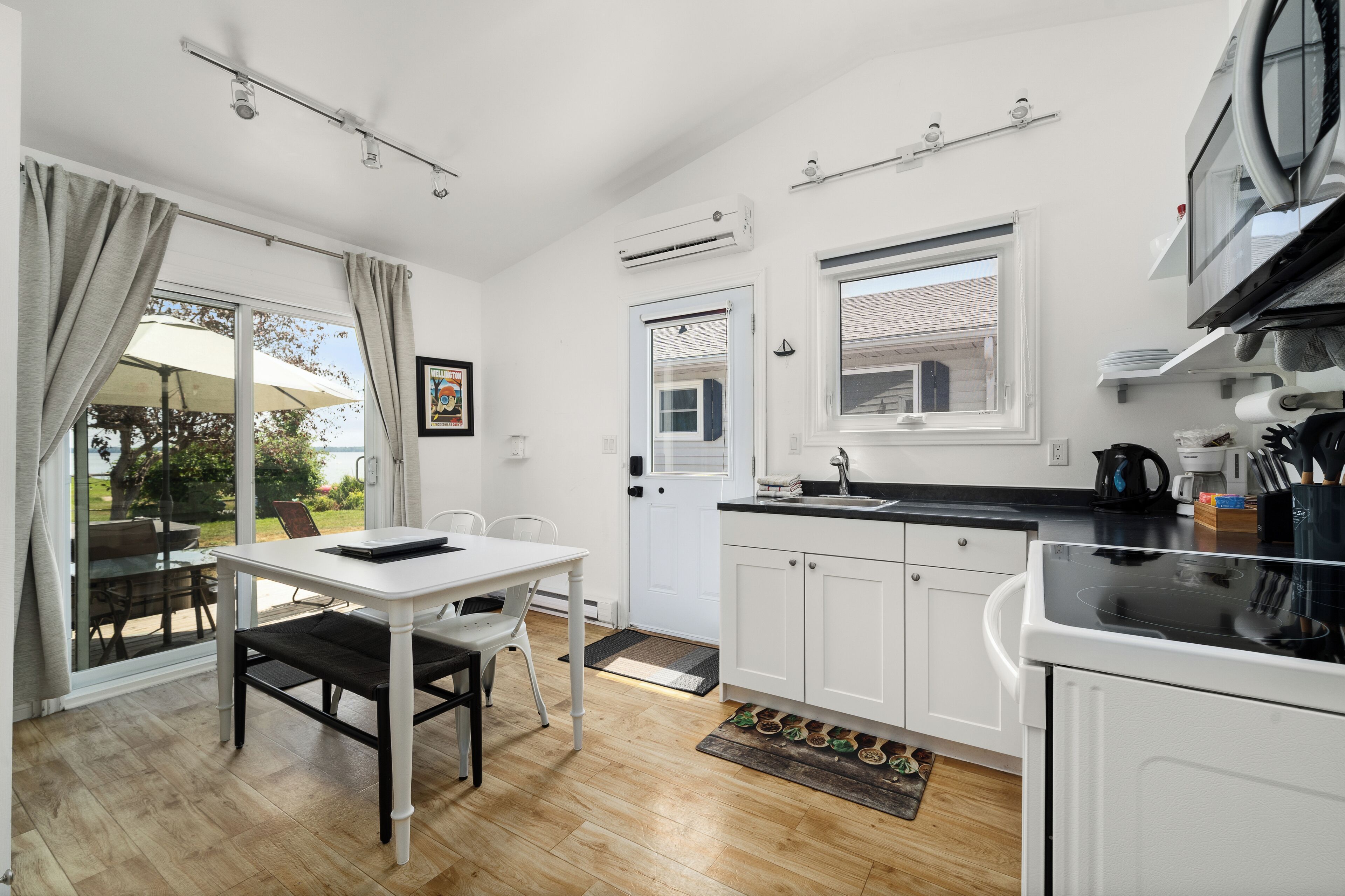 A modern kitchen with white cabinets, a black countertop, and a dining area with a white table and chairs.