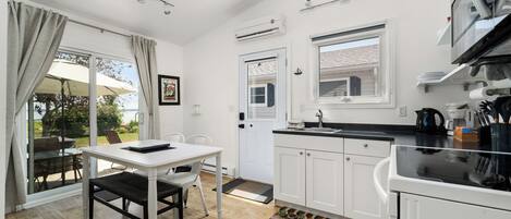 Una cocina moderna con armarios blancos, una encimera negra y un comedor con mesa y sillas blancas.