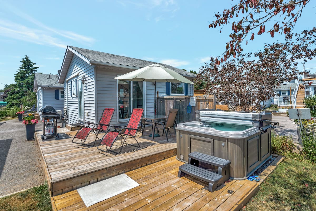 A wooden deck with a hot tub, outdoor seating, and a covered patio area.