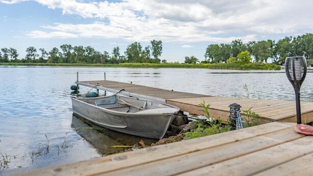 A wooden dock extending into calm water with a small boat moored at the end. - The Birch (Prince Edward)
