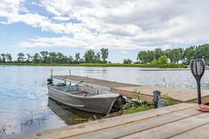 Un muelle de madera se adentra en aguas tranquilas, con un pequeño bote amarrado al final.