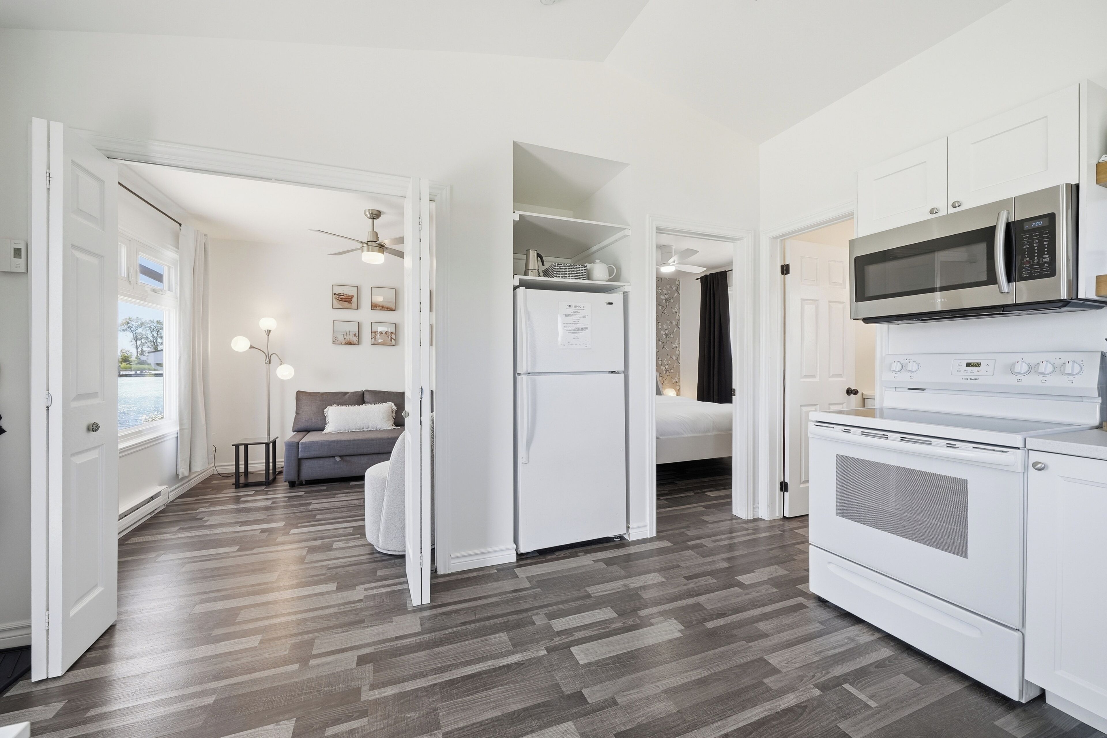 A compact kitchen with white cabinetry, a microwave, an oven, and a refrigerator.