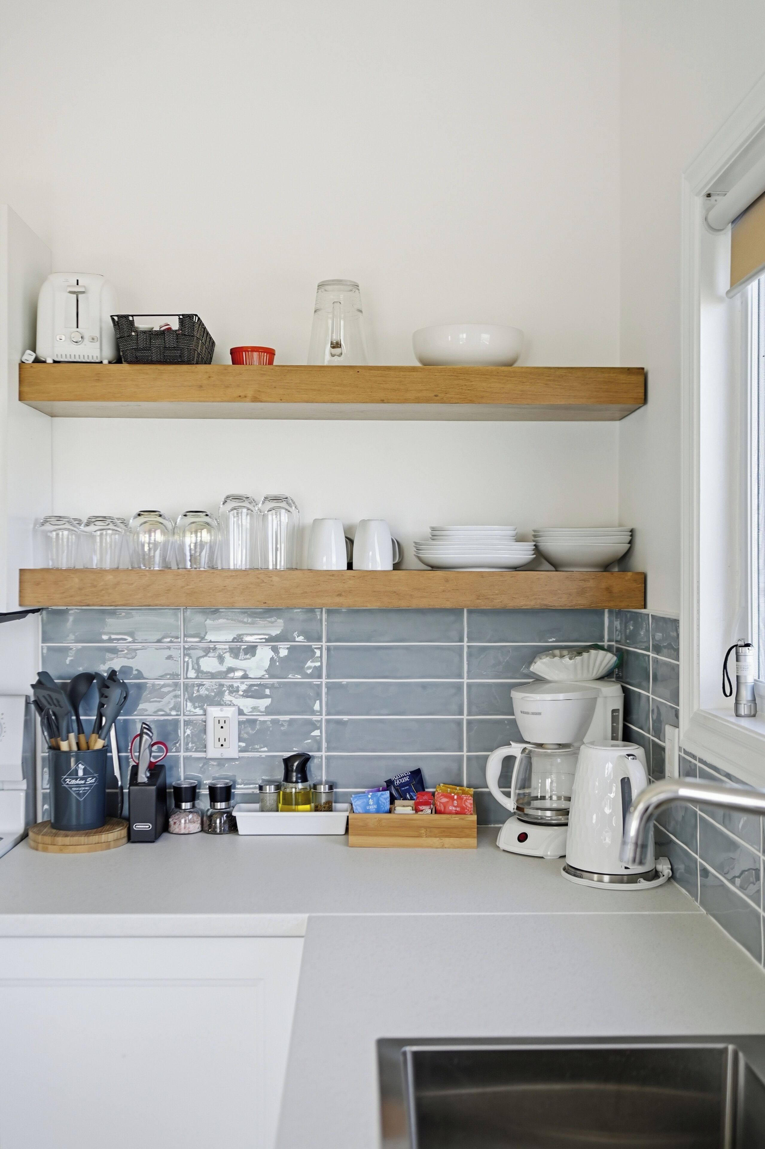 A kitchen with wooden shelves, a coffee maker, and a kettle.
