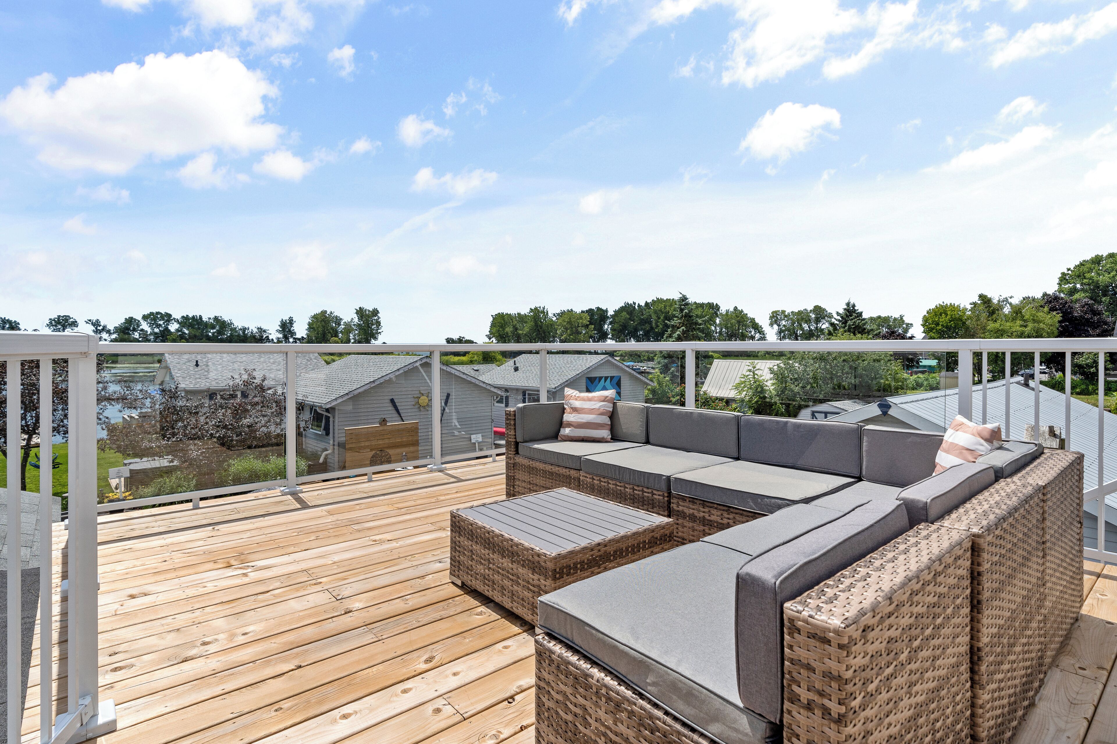 Une terrasse en bois, meublée de meubles en osier, avec vue sur un lac.