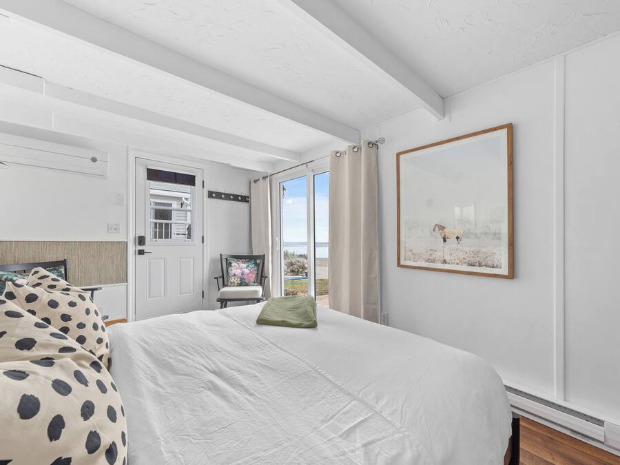 A bedroom with a bed, a desk, a chair, and a window with curtains.