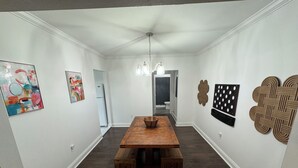Ein Essbereich mit Holztisch und Bänken, weißen Wänden und Kunstwerken.