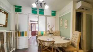 A dining area with a round table, chairs, a chandelier, and a view into another room.
