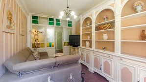 A living room with a sofa, a television, and a cabinet with shelves.