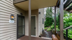 A house entrance with a door, a porch, and a garden area.