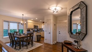 A modern kitchen with white cabinets, a dining area with a wooden table and chairs, and a large mirror on the wall.