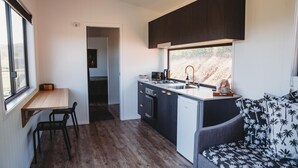 Cocina compacta con comedor, estufa integrada y ventana con vista a un paisaje natural.