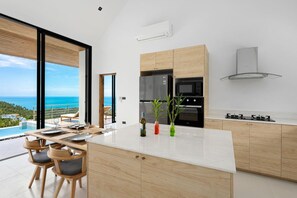 Eine moderne Küche mit einer großen Kochinsel, eingebauten Geräten und Blick aufs Meer.