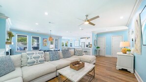 A spacious living room with a large sectional sofa, a coffee table, and a ceiling fan.