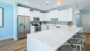 A modern kitchen with white cabinets, stainless steel appliances, and a large island with bar stools.