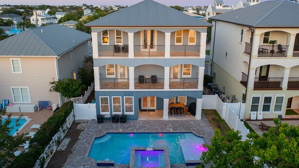 A two-story house with a swimming pool, balconies, and a view of neighboring houses.